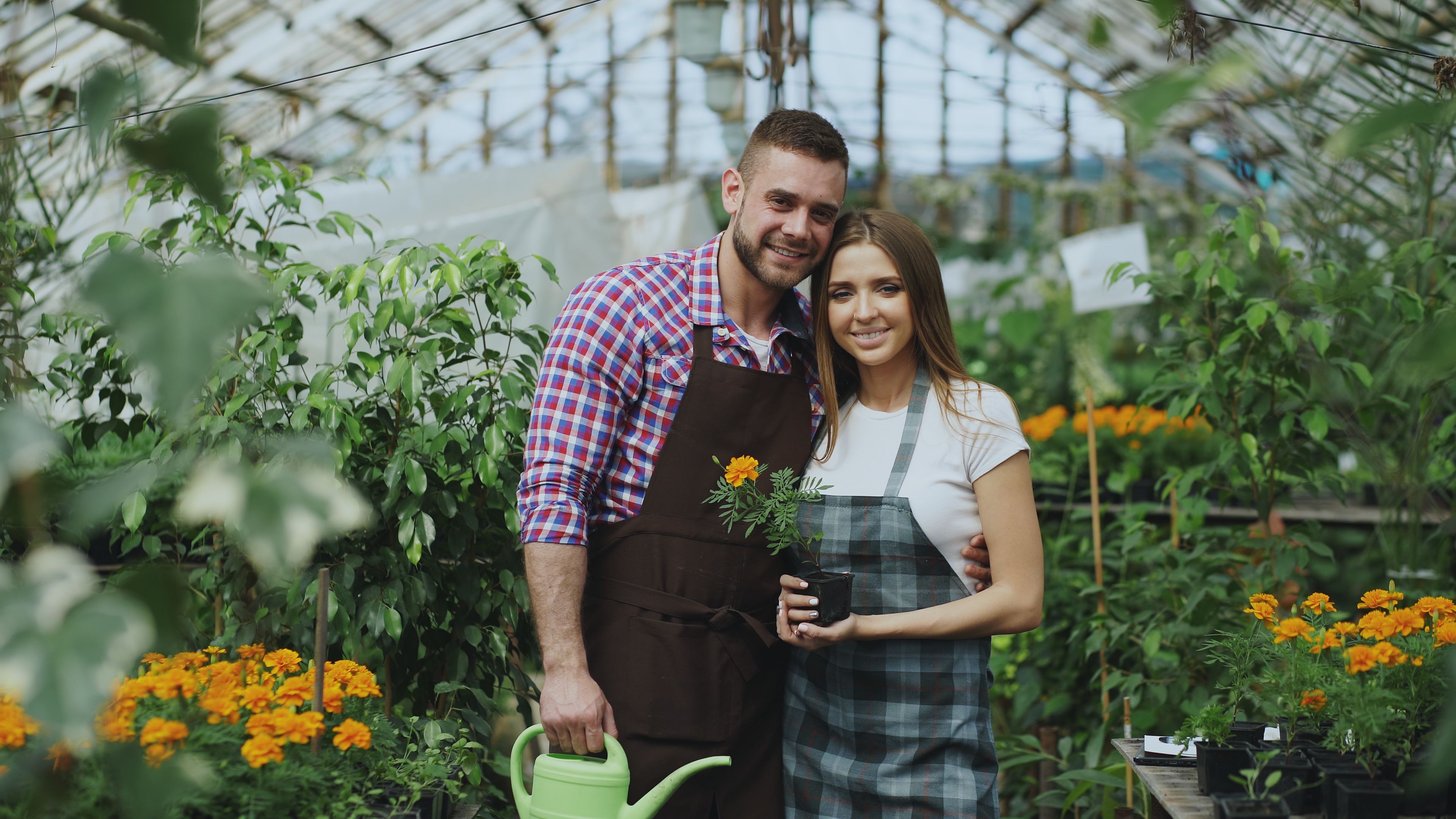 Twee mensen tussen de bloemen en planten in hun serre
